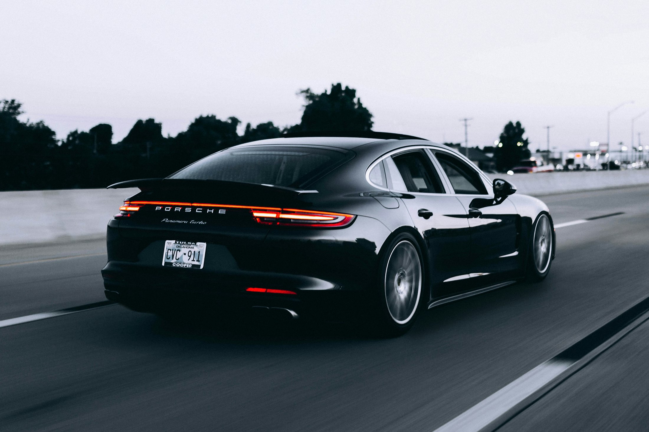 Porsche Panamera noire roulant sur une route au crépuscule